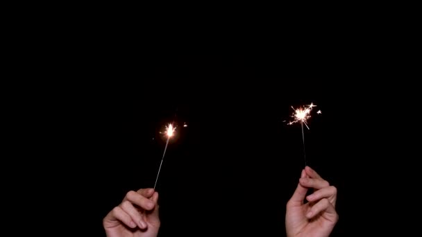 Dwie ręce trzymają i machają ogniem na ciemnym lub czarnym tle. Nowy rok lub koncepcja wakacji. — Wideo stockowe