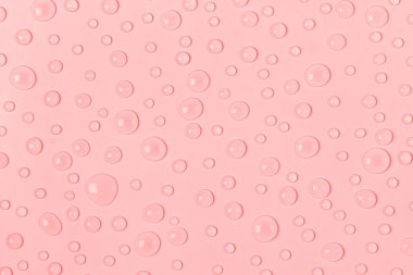 Su, pastel pembe arka plana damlıyor. Su dokusu kapanıyor. Arkaplan camı su damlalarıyla kaplı. Su kabarcıkları