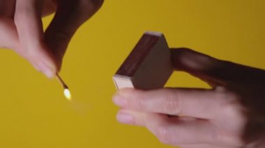 Sarı arka planda izole edilmiş kibriti çakan ellerin görüntüsünü kapat. Tam HD yavaş çekim videosu. Yeni Fikir kavramı