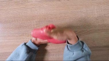 Çamurla oynamak, eğlence ve stres atmak için yapışkan maddeyi germek. Yaklaş ve üst görüntüde kırmızı, parlak balçık tutan ve sıkan kadın elini gör. 4K çözünürlük videosu