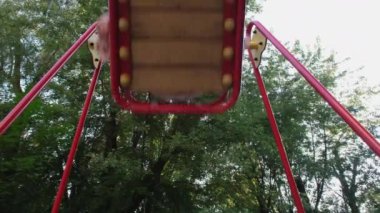 Mutlu ve gülümseyen genç kız salıncağa biniyor. Kız parkta salıncakta sallanırken eğleniyor. Boş zaman aktivitesi ve çocukluk konsepti. 4k çözünürlük videosu