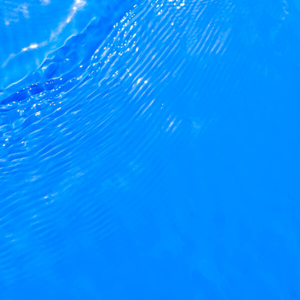 Surface of blue swimming pool water with light reflection. Texture of transparent blue water with ripples and waves in swimming pool. Trendy abstract nature background