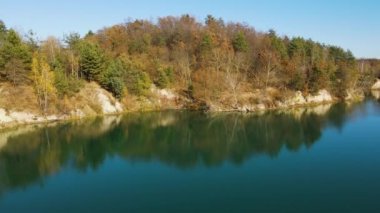 Temiz turkuaz su ve güzel sonbahar ormanıyla gölde drone görüntüsü. Altın ağaçlar ve göl üzerinde hava manzarası