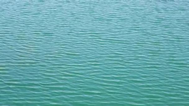 ターコイズブルーの湖でのシームレスなドローンビュー水の波紋が閉じます。美しい波のパターンを持つ海や海の上の空中ビュー夏の日に無限のアクアマリン水の風景ビュー — ストック動画