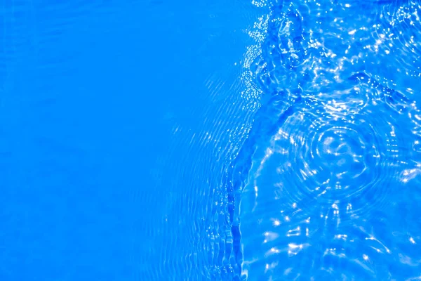 Επιφάνεια του μπλε νερό της πισίνας με αντανάκλαση φωτός. Υφή από διάφανο μπλε νερό με κυματισμούς και κύματα στην πισίνα. Μοντέρνο φόντο αφηρημένης φύσης — Φωτογραφία Αρχείου