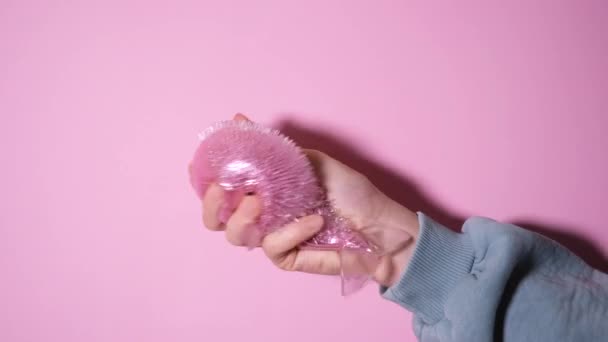 Рука играть с Сожмите розовую рыбу Запястье упражнения Антистрессовая игрушка. Рельефная игрушка на розовом фоне. Видео с разрешением 4k — стоковое видео