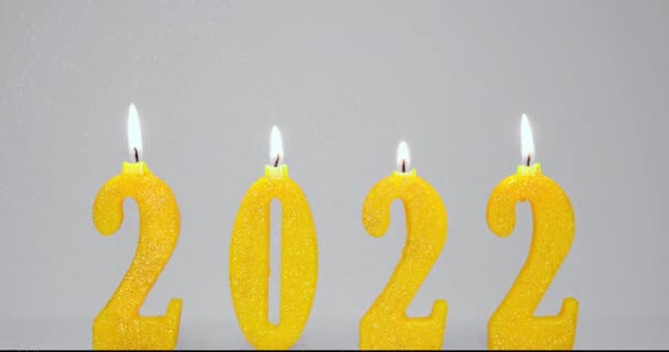 Fundo de férias de queimar velas amarelas 2022 e fogos de artifício Partículas. Feliz ano novo 2022 conceito. Lento em movimento Full HD vídeo. Queimando 2022 velas isoladas em fundo cinza. — Vídeo de Stock