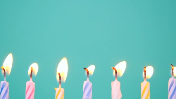 Happy Birthday koncept Made of Burning Barevné svíčky na modrém nebo tyrkysovém pozadí. Zapálení 7 let výročí narozeninové svíčky. Zpomalit plné HD video — Stock video