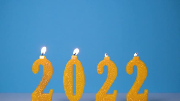 Fundo de férias de queimar velas amarelas 2022. Feliz ano novo 2022 conceito. Lento em movimento Full HD vídeo. Queimando 2022 velas isoladas em fundo azul — Vídeo de Stock