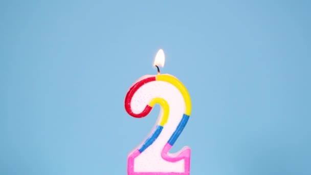 Banner de vídeo aniversário com queimando colorido número dois vela no fundo azul. Banner de aniversário de resolução de movimento lento Full HD. — Vídeo de Stock