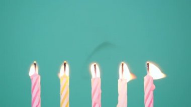 Mavi ya da turkuaz arka planda Yanan Renkli Mumlardan Yapılan Mutlu Yıllar konsepti. 5. yıl dönümü mumlarını üflüyorum. Yavaş çekim tam HD video