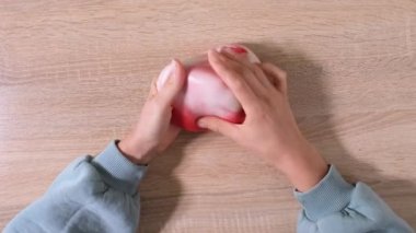 Çamurla oynamak, eğlence ve stres atmak için yapışkan maddeyi germek. Yaklaş ve üst görüntüde kadın eli kırmızı beyaz balçık tutuyor ve sıkıyor. 4K video