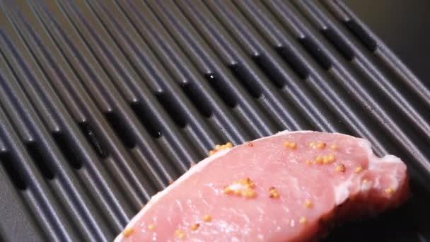 Hand lägger fläskstek på ytan av grillen. 4K upplösning video. Elektrisk grill och rått fläsk på nära håll. — Stockvideo