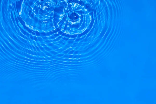 Επιφάνεια με βαθύ μπλε διάφανη υφή νερού πισίνας με κύκλους στο νερό. Μοντέρνο αφηρημένο φόντο της φύσης. Κύματα νερού στον ήλιο αντανακλάσεις φωτός. — Φωτογραφία Αρχείου