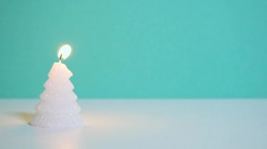 Beyaz Noel ağacı mumu mavi ya da turkuaz arka planda yanıyor. Ağır çekim tam HD video. Kopya alanı olan yeni yıl veya noel videosu pankartı