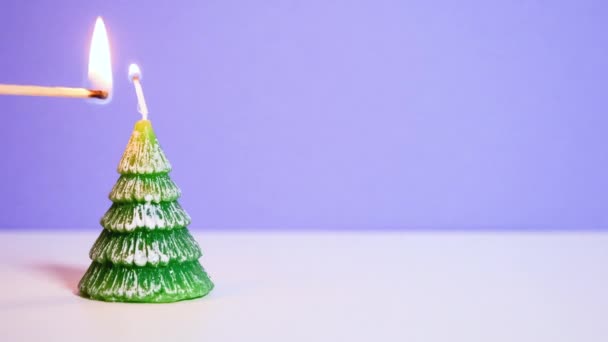 Groene kerstboom was kaars branden op lila achtergrond. Steek een kaars aan. Nieuwjaar of Kerst video banner met kopieerruimte. — Stockvideo