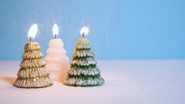 ゴールデン、ホワイト、グリーンのクリスマスツリーワックスキャンドルブルーの背景に燃える雪新年やコピースペース付きクリスマスビデオバナー. — ストック動画