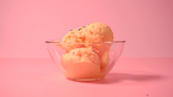Helado de mango en un tazón de vidrio. Una cucharada de helado de mango espolvoreada con polvo de azúcar de color. Helado con salpicaduras — Vídeos de Stock