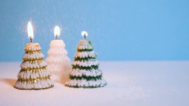 Mavi arka planda yanan altın, beyaz ve yeşil Noel ağacı mumuna kar yağması veya fotokopi alanı olan Noel videosu afişi.