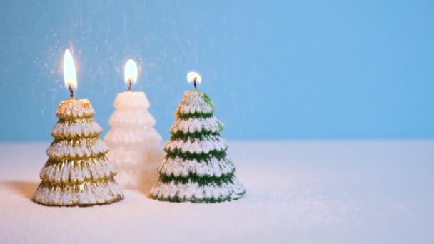 Χιόνισμα σε χρυσό, λευκό και πράσινο κερί χριστουγεννιάτικο δέντρο κερί καύση σε μπλε φόντο Πρωτοχρονιά ή τα Χριστούγεννα banner βίντεο με αντίγραφο χώρο. — Αρχείο Βίντεο