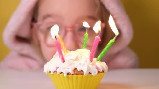 Ragazza felice bambino in tuta rosa soffia cinque candele sulla torta di compleanno alla festa. Avvicinati alla faccia della ragazza. rallentatore felice compleanno video banner — Video Stock