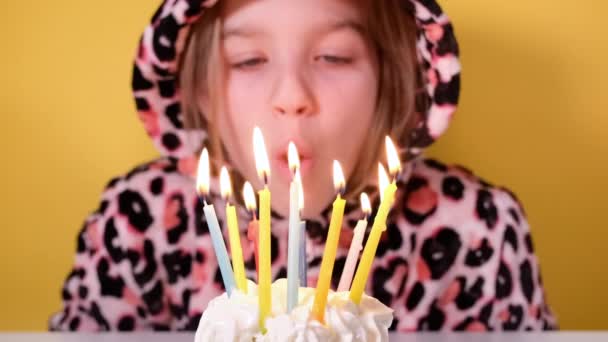 Šťastné dospívající dívka v leopard montérky sfoukne deset barevných svíček na narozeninový dortík na párty. Zblízka dívčí tvář. Zpomalit film Happy birthday video banner — Stock video