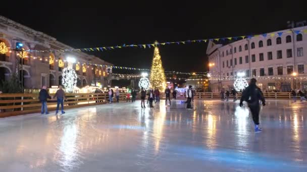 Mensen rijden op een schaatsbaan versierd met nieuwjaar en kerstvakantie. 4K resolutie video — Stockvideo