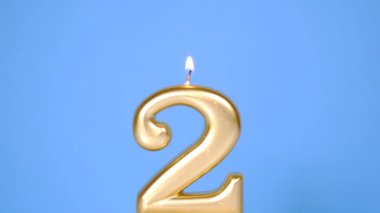 Mavi Arkaplan 'da yanan altın sarısı iki numaralı mum ile yıldönümü video afişi. 4K çözünürlük bayrağı.