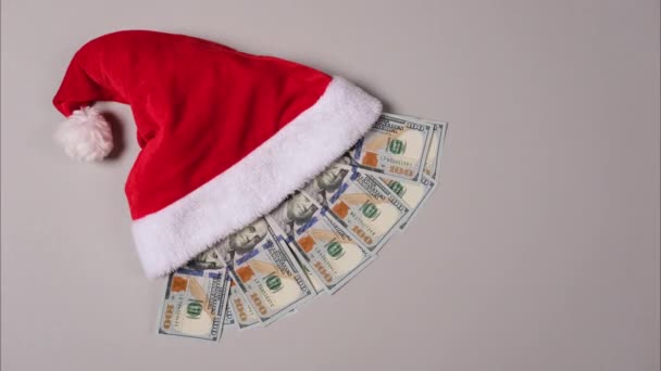 Nowy rok lub pomysł na prezent świąteczny. Pieniądze w kapeluszu Mikołaja. Świąteczny kapelusz pełen banknotów 100-dolarowych odizolowanych na biało. Stop wideo ruchu — Wideo stockowe