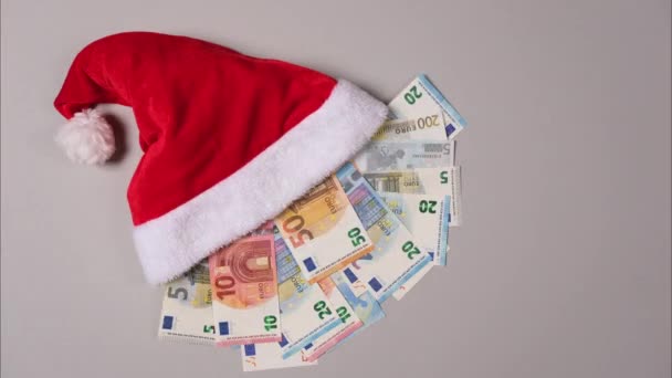 Nouvelle année ou concept de cadeau de Noël. L'argent dans le chapeau du Père Noël. Chapeau de Noël plein de billet d'euro isolé sur blanc. Stop motion video. Résolution 4k. — Video