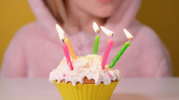 La niña feliz en el mono rosado sopla cinco velas en el pastel de cumpleaños en la fiesta. Primer plano en la cara de chica. Cámara lenta feliz cumpleaños video banner — Vídeos de Stock