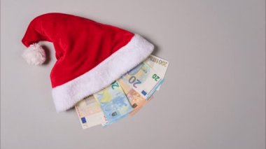 Yeni yıl ya da Noel hediyesi konsepti. Noel Baba şapkasının içindeki para. Avro banknotuyla dolu bir Noel şapkası beyaza izole edilmiş. Hareket videosunu durdur