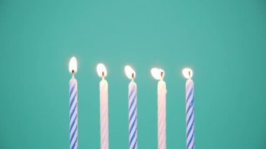 Mavi ya da turkuaz arka planda Yanan Renkli Mumlardan Yapılan Mutlu Yıllar konsepti. Beşinci yıl dönümü mumlarını yakmak. 4K çözünürlük videosu