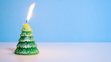 Mavi arkaplanda yanan yeşil Noel ağacı mumu ya da fotokopi alanı olan Noel videosu afişi.