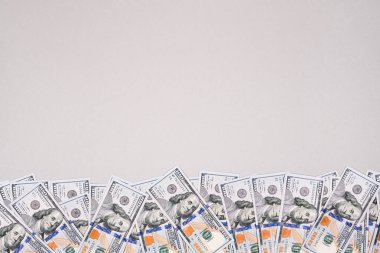 Gri arka planda 100 dolarlık banknotlar oynuyor. Kopya alanı olan parayla ilgili pankart.