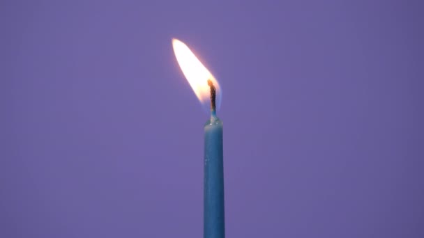 Blowing out one cake candle burning on a purple background. Close up on burning blue cake candle. Full HD resolution slow motion happy birthday or anniversary video banner. — Stockvideo