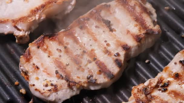 Close up view on Meat with golden crust is fried on an electric grill close up. 4K resolution video. Pork steaks close up are fried and smoked on the grill — Vídeo de Stock