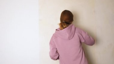 The girl covers the wall with wallpaper glue. Do the repair or renovation yourself concept. do-it-yourself repair. 4K resolution video