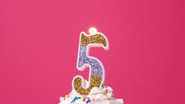 Tarta de cumpleaños con vela de colores ardientes número cinco sobre fondo rosa. Banner de vídeo de aniversario de cámara lenta. — Vídeos de Stock