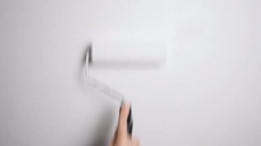Roller 'ın beyaz boyayla boyadığı duvar. Beyaz boyalı bir boya silgisiyle çıplak bir duvar boyamak. 4K çözünürlük videosu