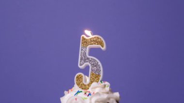 Mor arka planda yanan renkli mumlu doğum günü pastası. Yavaş çekim yıldönümü video pankartı