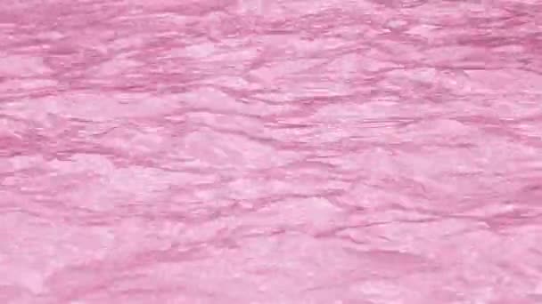 Rein transparent getönt in rosa Wasser im Schwimmbad mit Lichtreflexen. Video in 4k Auflösung. Textur des Wassers im Schwimmbad. — Stockvideo