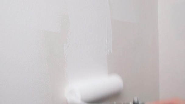 Rullmålning vägg med vit färg. Målar ut en naken vägg med en färg rulle med vit färg. 4K-video med upplösning. — Stockvideo
