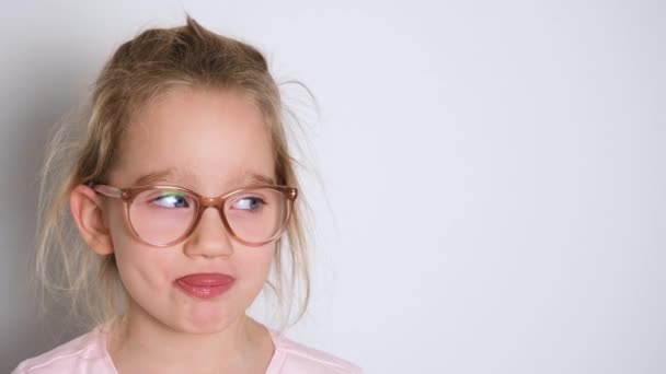 Gözlüklü ve pembe tişörtlü küçük kız eğleniyor ve kameraya yüzünü gösteriyor. Kopyalama alanı olan 4K çözünürlüklü video pankartı — Stok video