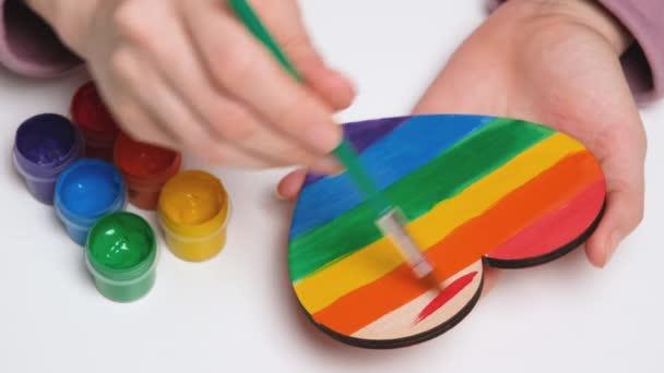 A mão pinta um coração de madeira em cores da Bandeira do Orgulho Gay. Símbolo colorido da LGBTQIA. Banner de vídeo de resolução 4K — Vídeo de Stock