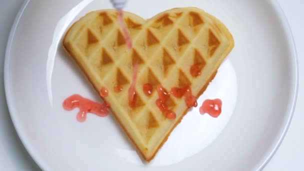 Nahaufnahme der hausgemachten herzförmigen Waffel mit Erdbeersirup. Romantisches Frühstück zum Valentinstag — Stockvideo