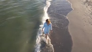 Karadeniz 'de terk edilmiş güzel bir plajın kenarında bir kız yürüyor. Deniz sahilinde yürüyen bir kadının ağır çekim HD videosu.