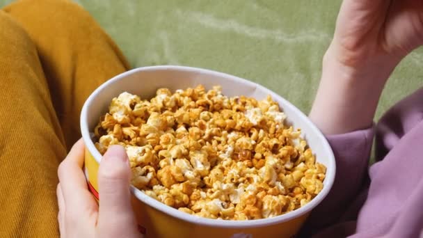 Vista da vicino sulla mano femminile che tiene un popcorn mentre guarda un film in salotto — Video Stock