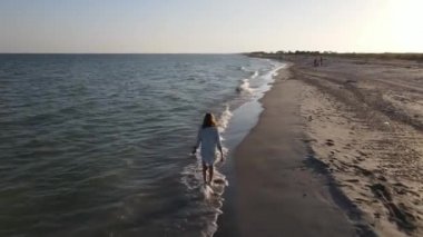 Karadeniz 'de terk edilmiş güzel bir plajın kenarında bir kız yürüyor. Deniz sahilinde yürüyen bir kadının ağır çekim HD videosu.