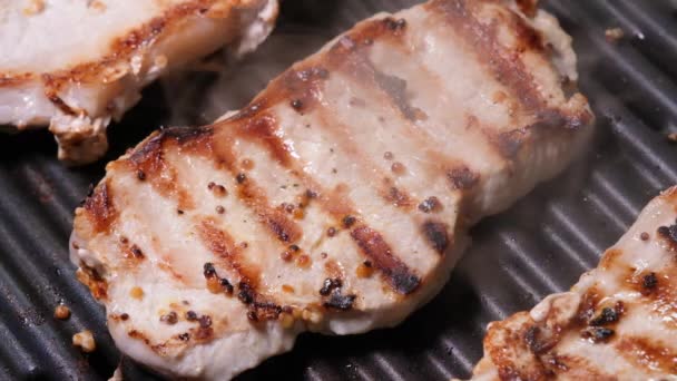 Close up view on Meat with golden crust is fried on an electric grill close up. 4K resolution video. Pork steaks close up are fried and smoked on the grill — Stockvideo